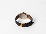 a black and gold watch sitting on top of a white surface