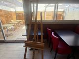 a painting easel in the middle of a room with a table and chairs