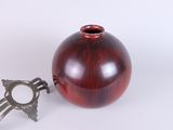 a red vase and a key on a white surface