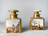 pair of antique oil bottles with paintings on them sitting on a table