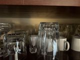 many glasses and cups on the counter in the kitchen