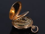 a gold pocket watch sitting on a black surface
