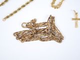 a lot of gold chains and a cross on a white surface
