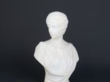 un petit buste en marbre blanc représentant une femme, sur fond noir
