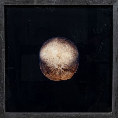 peinture représentant un objet rond dans un cadre noir sur fond noir