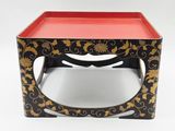 une table noire et dorée sur laquelle est posé un plateau rouge