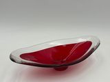 a red glass bowl sitting on a white surface