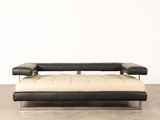 a black and white futon couch sitting on top of a cement floor