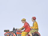 two figurines of a man and a woman riding on a motorcycle