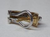un gros plan d'une bague en argent et en or posée sur une surface blanche