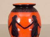 an orange vase with a black design on it