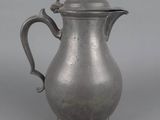 an old silver pitcher with a handle on a gray background