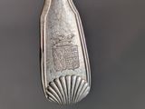 an old silver spoon with a silver handle hanging from it ' s side