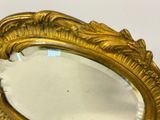 a mirror with a gold frame on a white surface