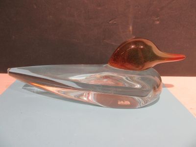 a glass duck sitting on top of a blue piece of paper
