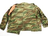 the back of a camouflage jacket with an orange patch on the chest