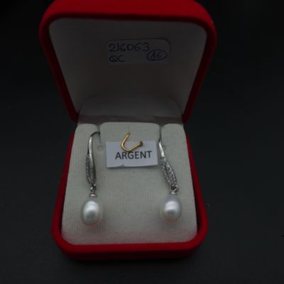 une paire de boucles d'oreilles dans une boîte rouge sur laquelle est apposée une étiquette avec un nom