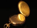 a close up of a gold pocket watch on a black surface