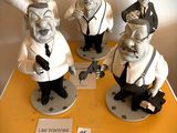 trois figurines représentant des hommes en costume-cravate posées sur une table jaune