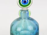 une bouteille en verre bleue surmontée d'un œil vert