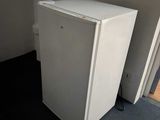 a small white refrigerator in the corner of a room