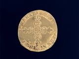 une vieille pièce d'or sur laquelle figure une croix, sur fond noir