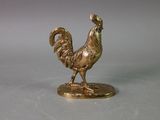 a gold rooster figurine sitting on top of a gold plate