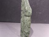 a close up of a green stone statue on a white surface