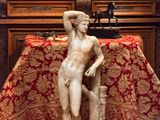 une statue représentant un homme assis sur une table recouverte d'une nappe rouge