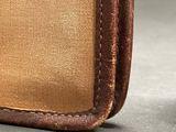 the inside of a brown and tan bag with a brown handle