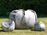 a sculpture of an elephant sitting in the grass next to some rocks