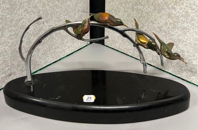 une sculpture métallique représentant un oiseau, posée sur un socle en verre