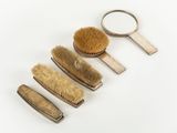 five brushes and a magnifying mirror on a white surface