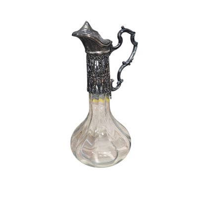 un pichet en verre muni d'une poignée en métal, sur fond blanc