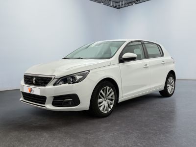La voiture blanche est garée dans une pièce au sol noir.