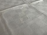 a close up of a bed with a white sheet with a monogram on it