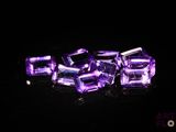 des cubes de cristal violets posés sur une surface noire, avec un fond noir