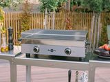 a stainless steel grill on a table with a plate of food on it