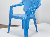 une chaise en plastique bleue posée sur une estrade blanche dans une pièce