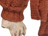 a statue of a hand holding a sweater on a mannequin