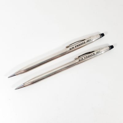 two pens sitting on top of a white table next to each other