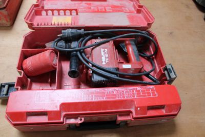 une boîte à outils rouge contenant une perceuse et d'autres outils