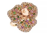 un gros plan d'une bague sertie d'une topaze rose entourée de pierres multicolores