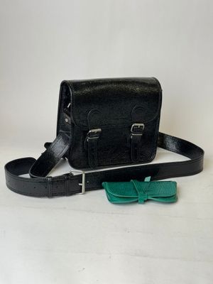 black leather bag with bow tie and glasses on white background