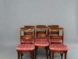 Six chaises aux assises rembourrées roses sont disposées devant un fond blanc.