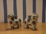 two figurines of dogs on a table with blue and white stripes
