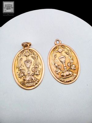two gold - plated saint benedict medal pendants on a white surface