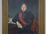 portrait of a woman in a black dress sitting on a red chair