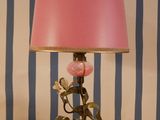 a pink lamp on a wooden table with a striped wall behind it