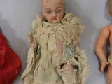 three dolls sitting next to each other on a white surface